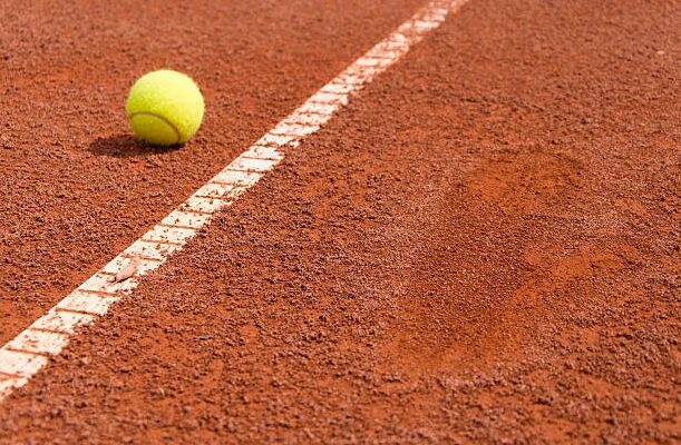 Tennis ball on clay with a footprint next to it Tennis ball on clay with a footprint next to it